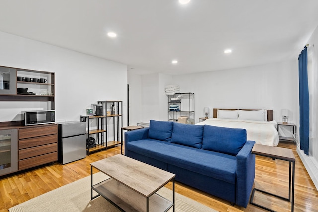 bedroom featuring recessed lighting, beverage cooler, light wood-type flooring, freestanding refrigerator, and a dry bar