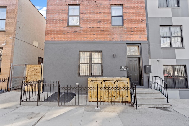 back of property with a fenced front yard, a gate, and stucco siding