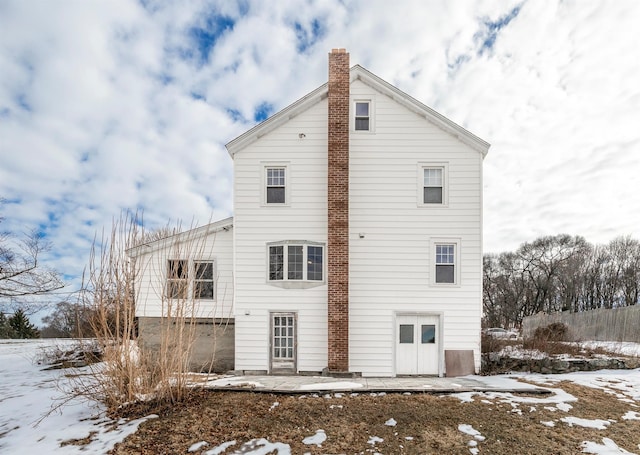 snow covered property with a patio area and a chimney