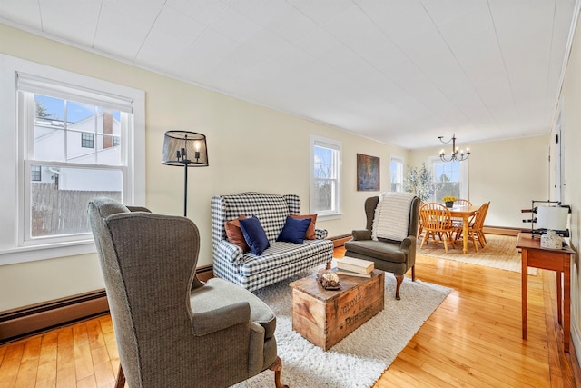 living room with baseboards, baseboard heating, light wood-type flooring, and an inviting chandelier