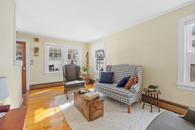 sitting room with light wood-type flooring, a baseboard radiator, and baseboards