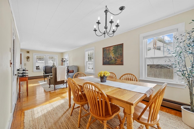 dining room featuring light wood finished floors, baseboards, and a notable chandelier