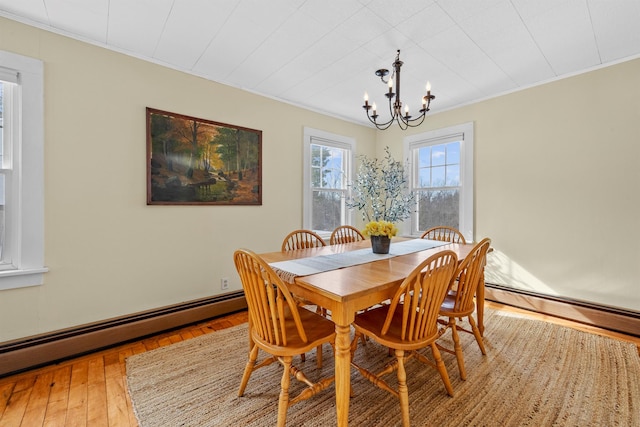 dining area with hardwood / wood-style floors, crown molding, a baseboard heating unit, and a notable chandelier