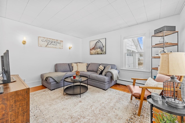 living area featuring baseboards, baseboard heating, and wood finished floors