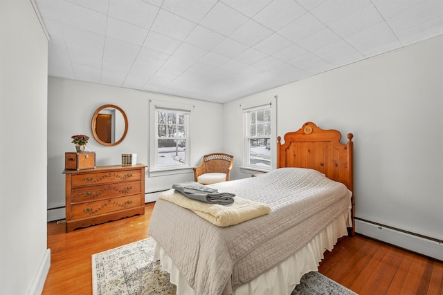 bedroom featuring baseboards, baseboard heating, and wood finished floors