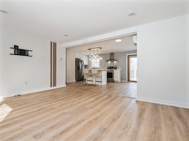 unfurnished living room featuring light wood-style floors, baseboards, and a sink