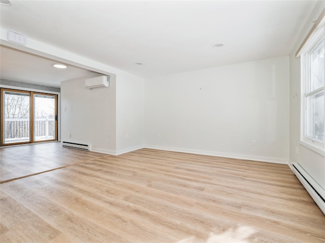 unfurnished room featuring a baseboard heating unit, light wood-type flooring, baseboards, and a wall mounted AC