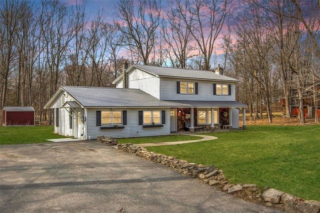 view of front of property with a lawn, a chimney, and metal roof