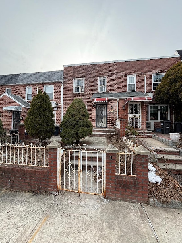 view of front of house featuring a fenced front yard, a gate, and brick siding