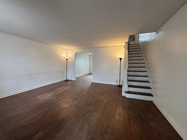 interior space featuring arched walkways, dark wood-type flooring, stairs, and baseboards