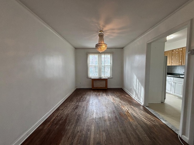 spare room with ornamental molding, dark wood-type flooring, and baseboards