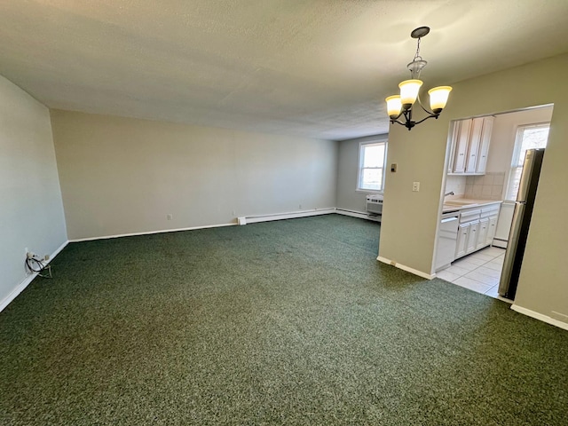 carpeted empty room with a chandelier, a textured ceiling, baseboard heating, and baseboards