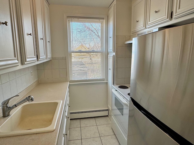 kitchen with light tile patterned floors, white electric range oven, a baseboard radiator, freestanding refrigerator, and a sink