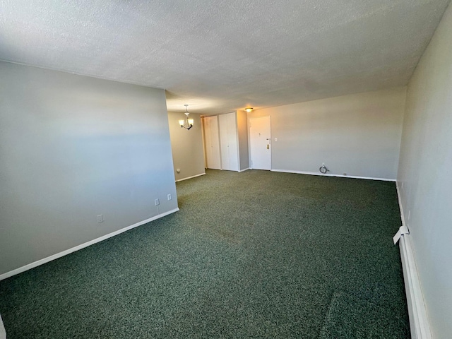 unfurnished room featuring a textured ceiling, carpet floors, baseboards, and a notable chandelier