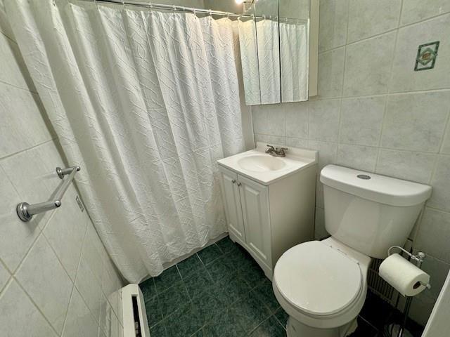 full bath with a shower with curtain, vanity, toilet, and tile walls