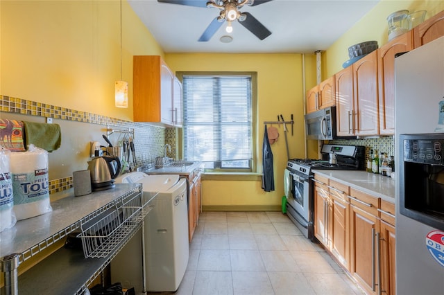 kitchen with pendant lighting, decorative backsplash, appliances with stainless steel finishes, light tile patterned flooring, and independent washer and dryer