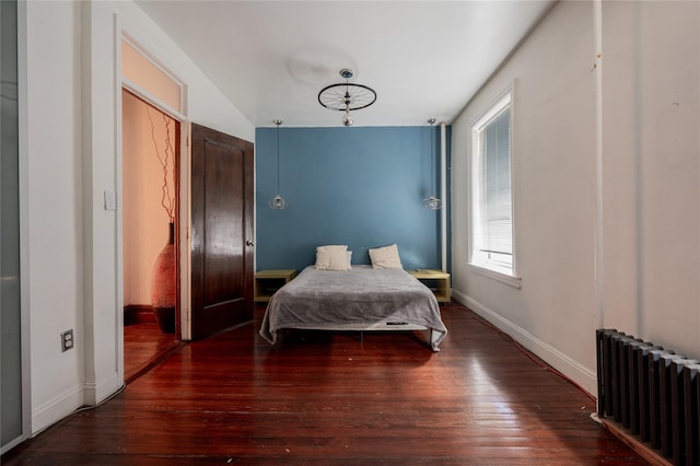 bedroom featuring dark wood-type flooring, baseboards, and radiator heating unit