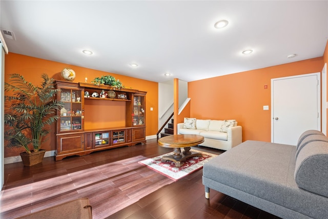 living room with stairs, dark wood-type flooring, visible vents, and recessed lighting