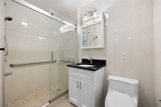 bathroom featuring tile walls, a shower stall, vanity, and toilet