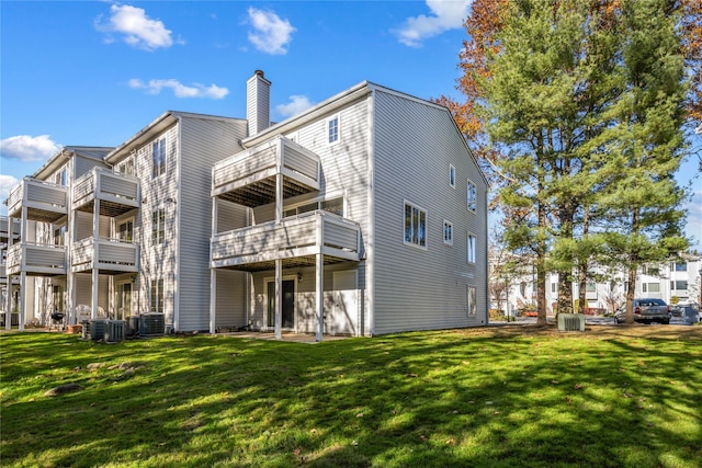 rear view of property featuring a yard, a chimney, and central air condition unit