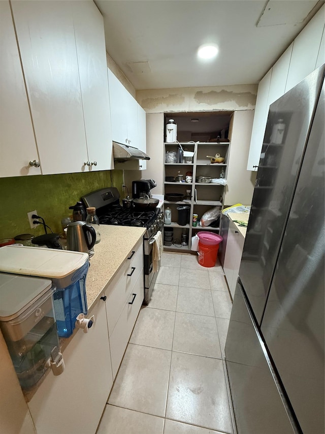 kitchen featuring stainless steel appliances, light countertops, under cabinet range hood, white cabinetry, and light tile patterned flooring