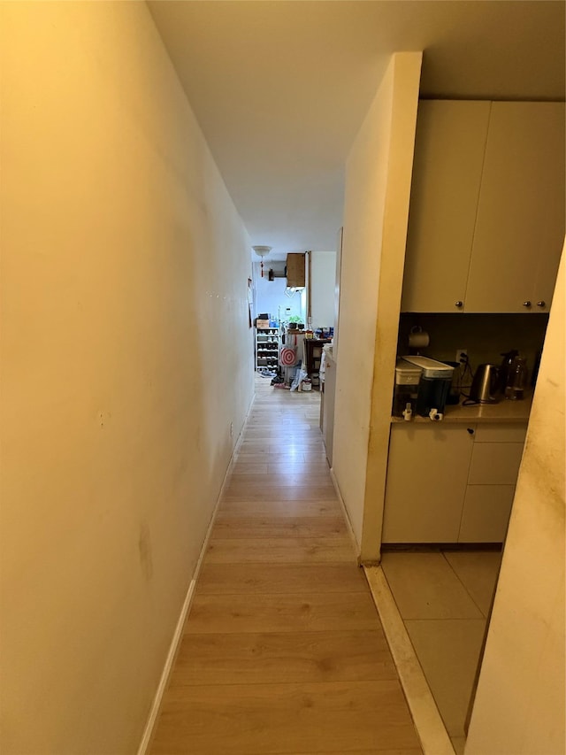 hall featuring light wood finished floors and baseboards