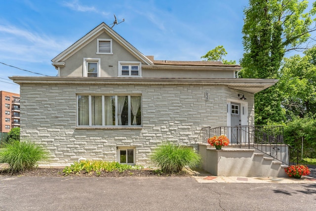 view of property exterior featuring stone siding and stucco siding