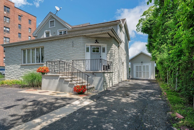 view of front of house with a garage, stone siding, and an outdoor structure