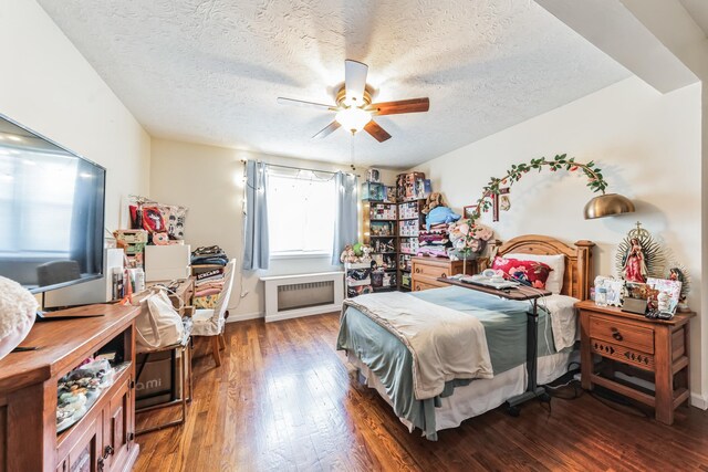 bedroom with dark wood-style floors, radiator heating unit, ceiling fan, a textured ceiling, and baseboards