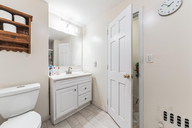 bathroom with toilet, vanity, and baseboards