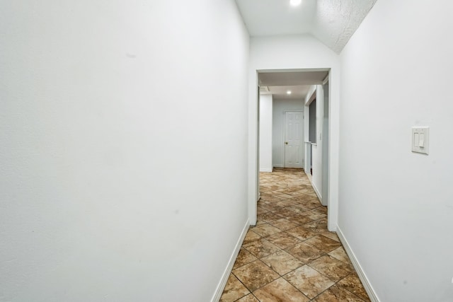 hall featuring lofted ceiling and baseboards