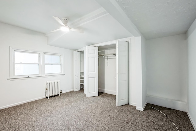 unfurnished bedroom with carpet, a closet, radiator heating unit, ceiling fan, and baseboards