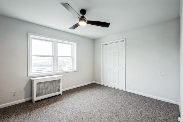 unfurnished bedroom with radiator heating unit, carpet, a closet, and baseboards