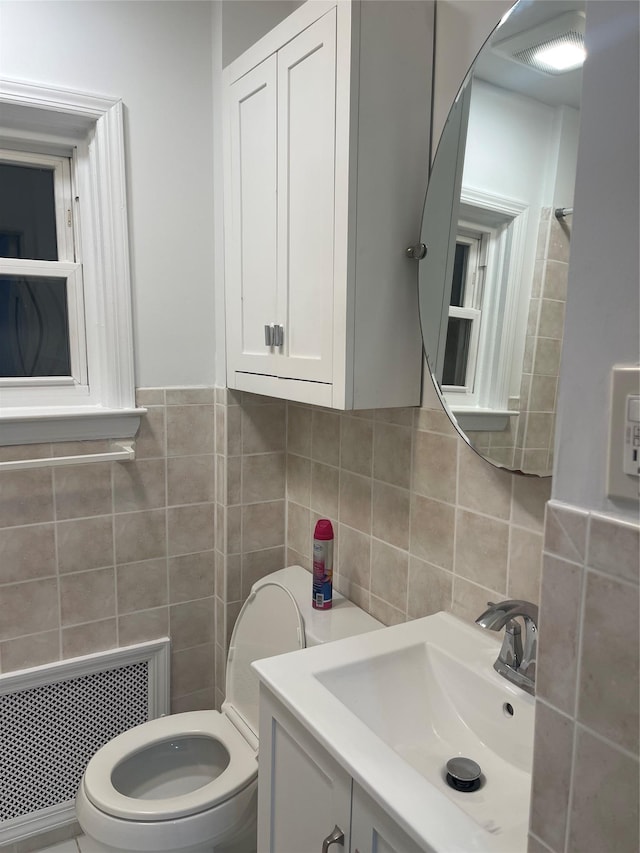 bathroom featuring toilet, tile walls, radiator heating unit, and vanity