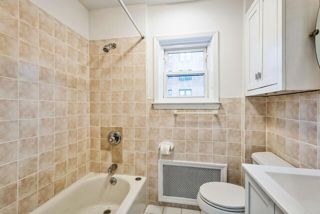 bathroom featuring radiator, tub / shower combination, tile walls, and toilet