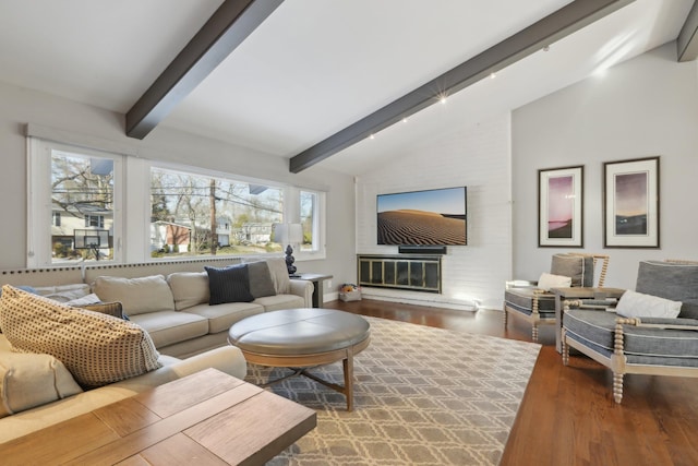 living room featuring vaulted ceiling with beams, a fireplace, and wood finished floors