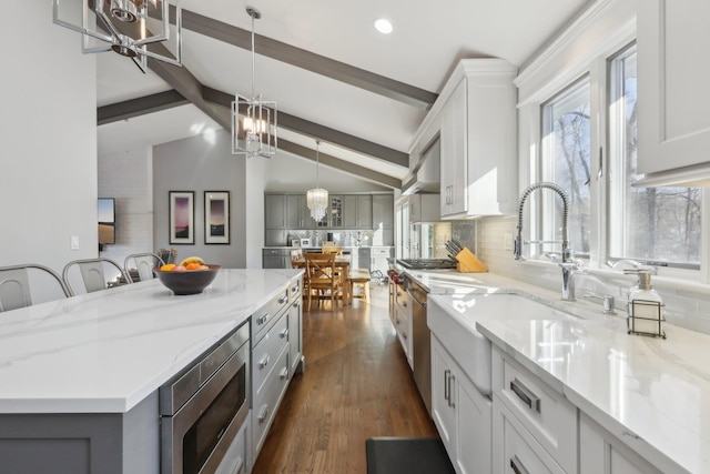 kitchen featuring a breakfast bar, light stone countertops, stainless steel appliances, white cabinetry, and pendant lighting