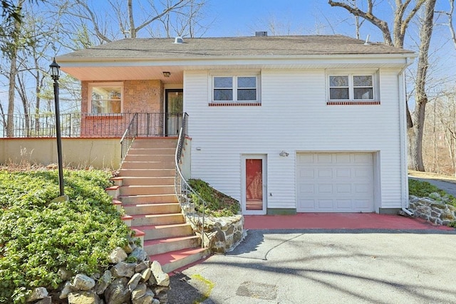 view of front of property featuring stairway, a garage, and aphalt driveway