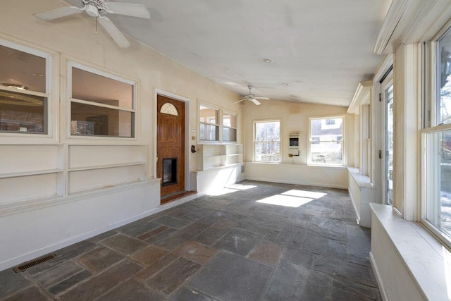 unfurnished sunroom featuring visible vents, lofted ceiling, ceiling fan, and a fireplace