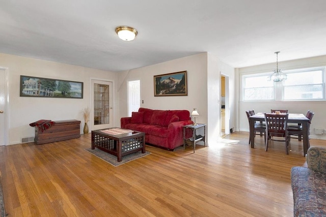 living area featuring light wood-type flooring, visible vents, and a chandelier