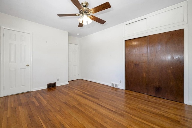 unfurnished bedroom with ceiling fan, visible vents, baseboards, and hardwood / wood-style floors