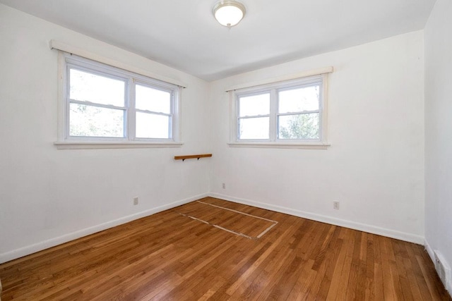 spare room with hardwood / wood-style flooring, plenty of natural light, and baseboards