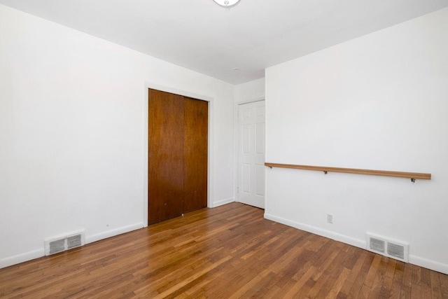 spare room with visible vents, baseboards, and wood finished floors