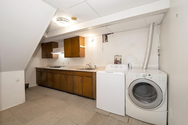 clothes washing area with laundry area, independent washer and dryer, light floors, and a sink