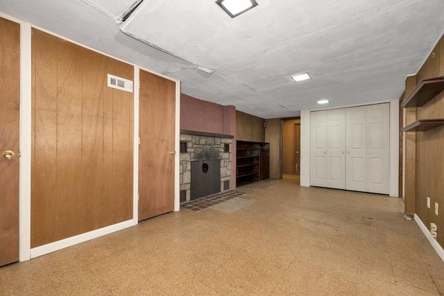 finished basement featuring tile patterned floors, visible vents, baseboards, and wooden walls