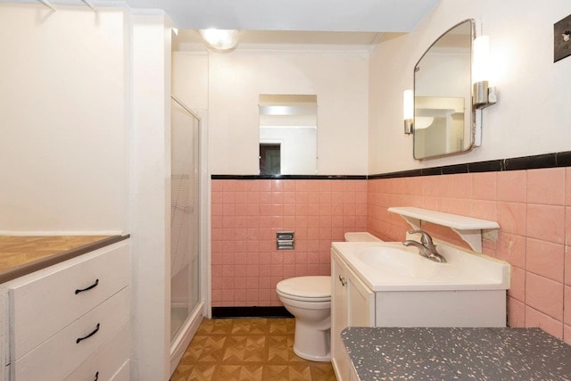 full bathroom featuring wainscoting, a stall shower, toilet, and tile walls