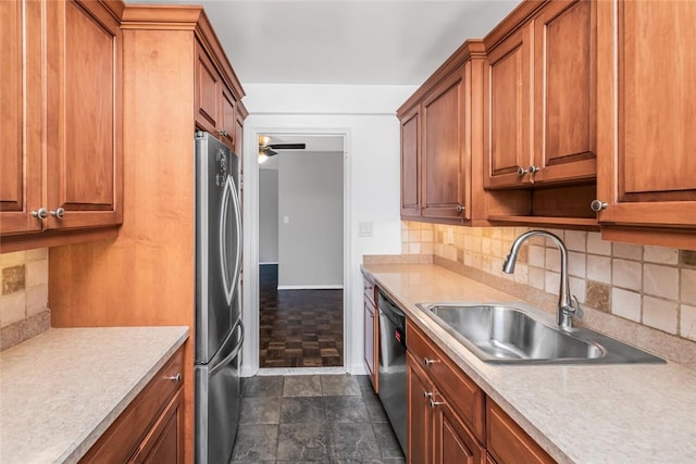 kitchen with dishwashing machine, a sink, light countertops, freestanding refrigerator, and brown cabinetry