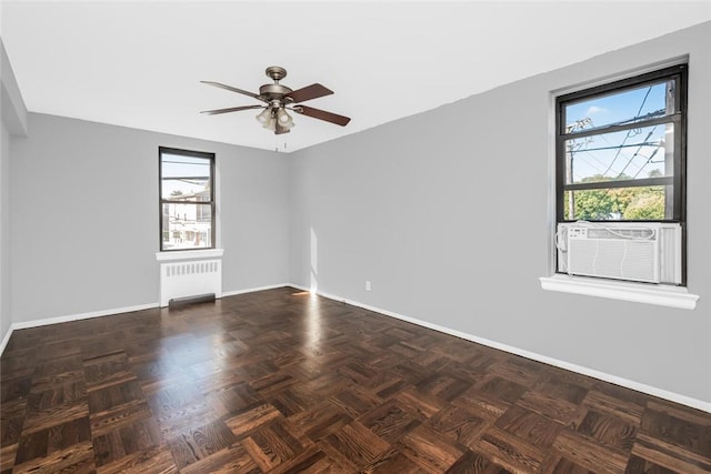 empty room featuring ceiling fan, radiator heating unit, cooling unit, and baseboards