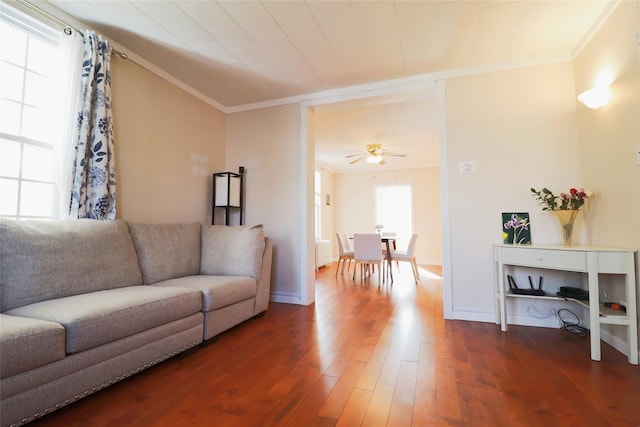 living room with a ceiling fan, baseboards, ornamental molding, and wood finished floors