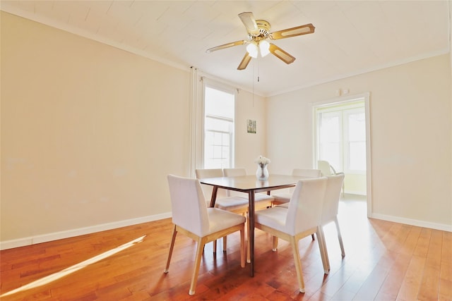 dining room with crown molding, wood finished floors, a ceiling fan, and baseboards